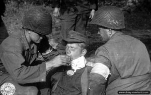 Des infirmiers américains prennent en charge un soldat allemand blessé au cou dans le secteur de Bricquebec. Photo : US National Archives
