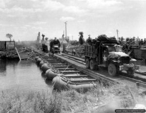 17 juin 1944 : des camions GMC CCKW 353 traversent un pont flottant de type Steel Treadway Bridge installé par le génie à Isigny-sur-Mer. Photo : US National Archives