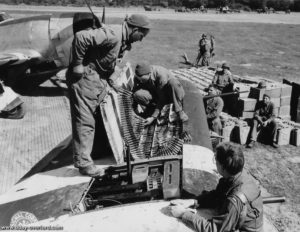 Des mécaniciens de la 9th (US) Air Force installent des bandes de 12,7 mm dans les ailes d’un chasseur P-47 Thunderbolt. Photo : US National Archives