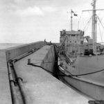 Photos of Port-en-Bessin in 1944 3 Un navire tanker accosté au môle ouest de Port-en-Bessin alimente les réserves de carburant du "minor system" (opération PLUTO). Photo : US National Archives