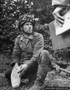 Un prisonnier allemand appartenant à la Luftwaffe se déséquipe sur ordre de soldats américains près de Saint-Georges-d’Elle. Photo : US National Archives