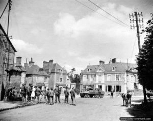 12 juin 1944 : Marie-Esther Duchenes, volontaire de la Croix Rouge avec des personnels d’une Engineer Special Brigade devant la fontaine de Sainte-Marie-du-Mont. Photo : US National Archives