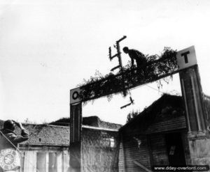 22 juin 1944 : destruction d’une croix gammée à l’entrée des installations de l’organisation Todt à Valognes. Photo : US National Archives