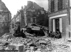 Des soldats du 317ème régiment de la 80ème division d’infanterie américaine, rue de la Poterie à Argentan, à proximité de l’épave d’un char Panther abandonné. Photo : US National Archives