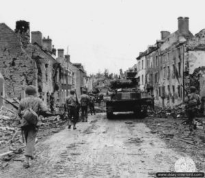 Des soldats du 117ème régiment de la 30ème division d’infanterie américaine appuyés par deux chars Sherman du 743rd Tank Battalion progressent dans les ruines de Saint-Fromond. Photo : US National Archives