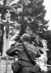 14 juin 1944 : un soldat observe le calvaire de la Galie à Sainte-Marie-du-Mont. Photo : US National Archives