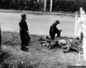 Adjutor et Marie Lecanu se recueillent sur la dépouille d'un soldat américain sur la route d'Isigny à Saint Hilaire Petitville. Ils sont filmés et photographiés à cette occasion par les services américains. Photo : US National Archives