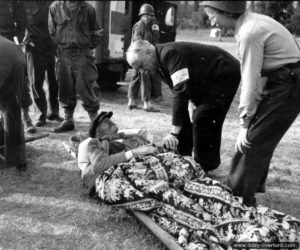 15 juin 1944 : le médecin L. Rivière et une volontaire de la Croix Rouge, Kathleen Knight, prennent en charge à Sainte-Marie-du-Mont un réfugié normand âgé. Photo : US National Archives