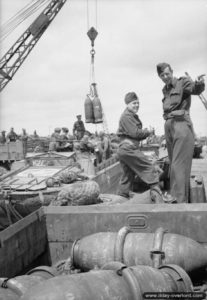 Des personnels de la RAF à Gold Beach observent le déchargement de réservoirs largables embarqués à bord de véhicules amphibies DUKW . Photo : IWM