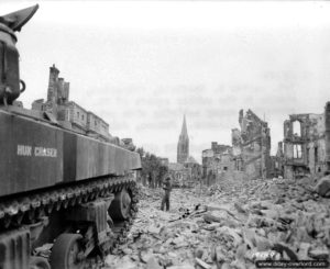 18 juillet 1944 : un char Sherman baptisé "Hun" appartenant à l’escadron de commandement du 747th Tank Battalion rattaché à la 29ème division d’infanterie, au milieu des ruines de Saint-Lô. Photo : US National Archives