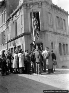 Le long de la rue Octave Mirbeau, l’étude de Maître Charles Pommier, notaire et maire de Trévières, est décorée des drapeaux alliés. Photo : US National Archives