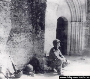 Un para du 506th PIR au pied de l'église de Sainte-Marie-du-Mont observe des escadrilles en vol. Photo : US National Archives