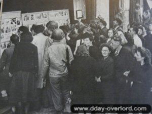 8 juillet 1944 : des civils observent les actualités militaires en photos dans une vitrine à Cherbourg. Photo : US National Archives