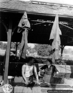 Alexandrine Françoise en pleine discussion avec le caporal D. W. Hyde au lavoir de Trévières. Photo : US National Archives