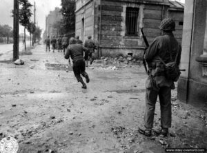 Des soldats américains avenue de Paris traversent une rue en prenant en compte le risque des tireurs isolés à Cherbourg. Photo : US National Archives