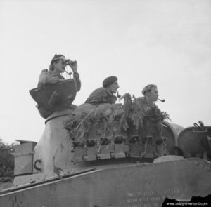 21 août 1944 : l’équipage d’un char Sherman observe la ligne de front dans le secteur d’Argentan, toutes pipes sorties. Des chenilles de char Panther servent comme protection. Photo : IWM