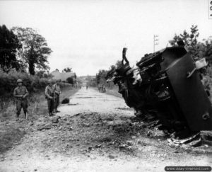 9 juillet 1944 : un véhicule M8 Greyhound détruit sur la D900 à l’entrée nord a été basculé sur le bas-côté dans le secteur de La-Haye-du-Puits. Photo : US National Archives