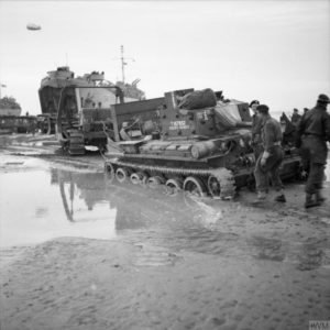 14 juin 1944 : un char Cromwell Mk IV "Satan's Chariot" du 5th RTR, 7th Armoured Division, est remorqué par un char bulldozer sur Gold Beach. Photo : IWM B 5580