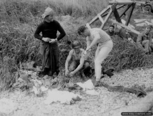 12 juin 1944 : 1st Lieutenant Morris W. Self et le soldat James E. Stanton se changent après avoir été en mer pour secourir des naufragés d'un LCVP. Photo : US National Archives