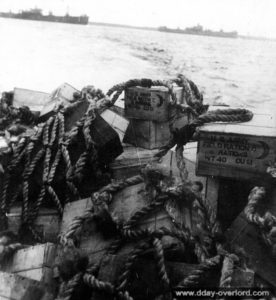 Des caisses de rations américaines sont transportées dans la rade de Cherbourg afin d'être débarquées. Photo : US National Archives