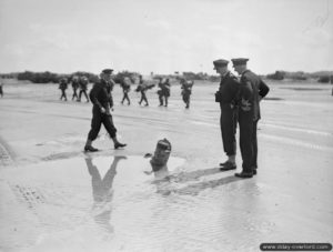 Le Commodore Douglas-Pennant de la Royal Navy observe les vestiges d'un obstacle de plage à Gold Beach. Photo : IWM