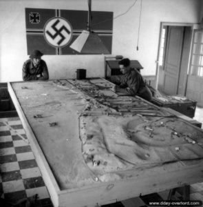 Dans un bâtiment de Courseulles, des canadiens inspectent une maquette utilisée par les Allemands. Photo : IWM