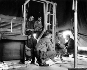 Installation d’un standard téléphonique de type Switchboard 58 par des transmetteurs américains à l’hôpital de campagne de Saint-Hilaire-Petitville. Photo : US National Archives