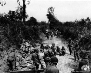 20 juillet 1944 : des soldats constatent les dégâts causés par une mine sur une route à l’est de Saint-Lô. Photo : US National Archives