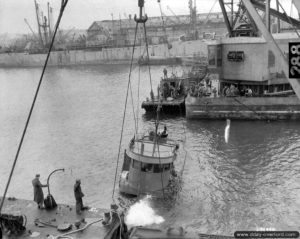 Une grue soulève un bateau coulé dans le port de Cherbourg. Photo : US National Archives