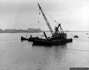 Une grue à flèche relève des épaves dans la rade de Cherbourg. Photo : US National Archives