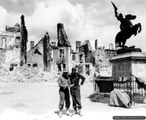 Deux soldats au pied de la statue de Jeanne d’Arc, sur la place du même nom à Montebourg. Photo : US National Archives