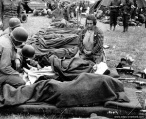 Des médecins américains prennent en charge une petite normande blessée qui est surveillée par sa mère. Le site accueille plusieurs blessés qui sont triés avant leur évacuation. Photo : US National Archives