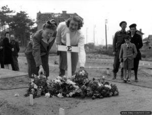 Des Normands fleurissent la tombe d'un soldat canadien à Bernières-sur-Mer. Photo : Archives Canada
