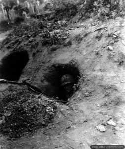 23 juillet 1944 : le sergent E. Vandenburg de la 35ème division d’infanterie monte la garde depuis un trou creusé par les Allemands aux abords du cimetière de Saint-Lô. Photo : US National Archives