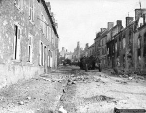 Un convoi américain progresse rue de Carentan à Montebourg. En queue de colonne, un half-track remorque un canon antichar M5 de 76,2mm. Photo : US National Archives