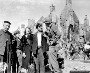 Place Gambetta : un soldat observe l’insigne de l’infanterie américaine fièrement portée par un habitant d’Isigny. Photo : US National Archives