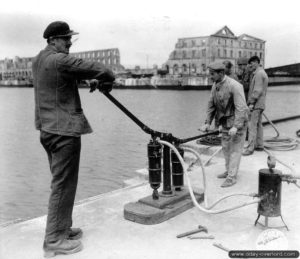 Les civils normands aident à fournir de l’oxygène avec une pompe à air aux scaphandriers à Cherbourg. Photo : US National Archives