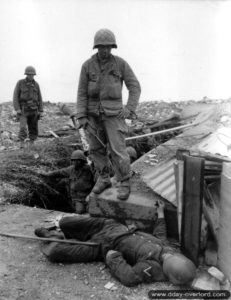 Des soldats américains de la 79ème division d’infanterie américaine dans les positions allemandes avant le fort du Roule à Cherbourg, où repose un cadavre allemand. Photo : US National Archives
