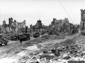 Des convois américains à travers les ruines de la place Gambetta à Isigny-sur-Mer. Photo : US National Archives