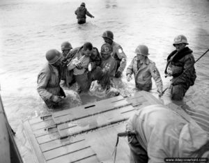 Des infirmiers du 2nd Naval Beach Battalion évacuent un parachutiste blessés à bord d'un LCVP. Photo : US National Archives