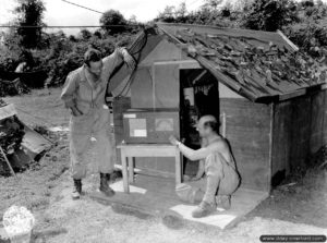 Des soldats écoutent la radio sur un lieu de bivouac amélioré dans le secteur de Cherbourg. Photo : US National Archives