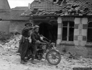 15 juin 1944 : dans Rots, le caporal Philippe Castailloux, estafette du régiment de la Chaudière, se renseigne auprès du sergent T. S. Giles appartenant à la Numero 4 Provost Company. Photo : US National Archives