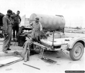 Des militaires américains s'affairent autour d'une remorque de 20 mm Flak 38 à Cherbourg. En arrière-plan, une citerne à eau allemande. Photo : US National Archives