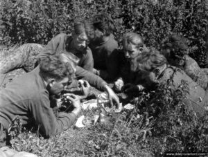 15 juin 1944 : des des prisonniers allemands surveillés par des Canadiens partagent un repas dans le secteur de Rots. Photo : US National Archives
