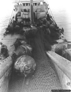 Relève d’un filet métallique anti-sous-marins allemand à bord de l’USS Pinon à Cherbourg. Photo : US National Archives