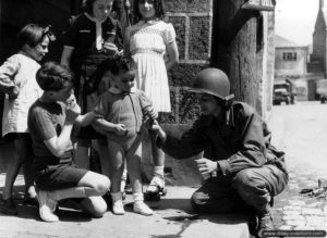 Une WAC (Woman Army Corps) prend un peu de temps avec des enfants de Carentan. Photo : US National Archives
