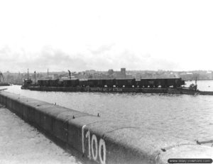 26 juillet 1944 : une rame de wagons sur une barge tractée par un remorqueur à Cherbourg. Photo : US National Archives