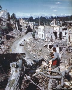 Deux jeunes habitants de Saint-Lô (Max Robin, 13 ans et pull gris, avec son jeune frère de 9 ans) observent une Citroën traction traversant la rue des Noyers à Saint-Lô. Photo : US National Archives