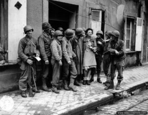 26 juin 1944 : des soldats américains de la 79th Infantry Division encadre une habitante de Cherbourg. Photo : US National Archives