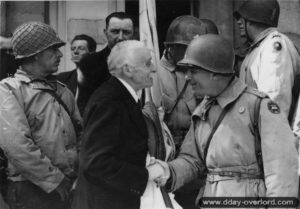 27 juin 1944 : cérémonie de la libération devant de l’hôtel de ville de Cherbourg et poignée de mains entre le maire, le docteur Paul Renault, et le Major General Manton S. Eddy commandant de la 9ème division d’infanterie. Photo : US National Archives
